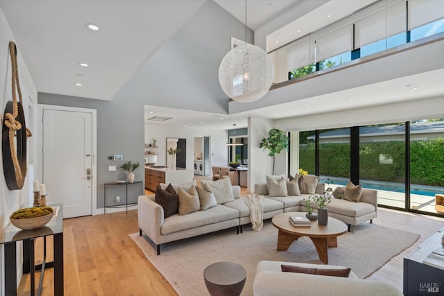 living area featuring recessed lighting, a towering ceiling, and light wood finished floors