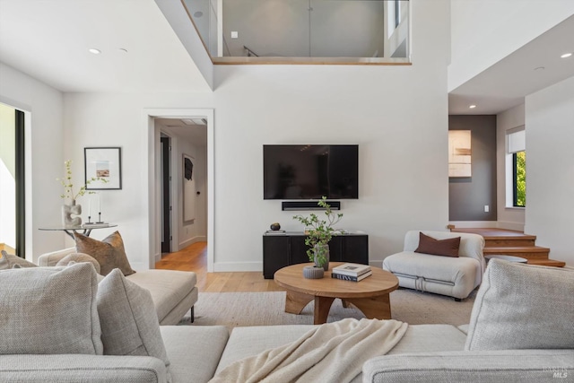 living room with light wood-style floors, recessed lighting, a high ceiling, and baseboards