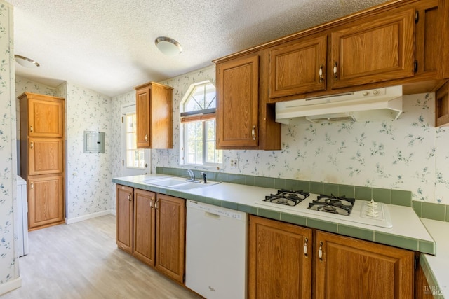 kitchen featuring dishwasher, light hardwood / wood-style flooring, sink, tile counters, and a textured ceiling