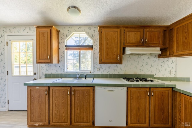 kitchen with tile counters, sink, white appliances, and a textured ceiling