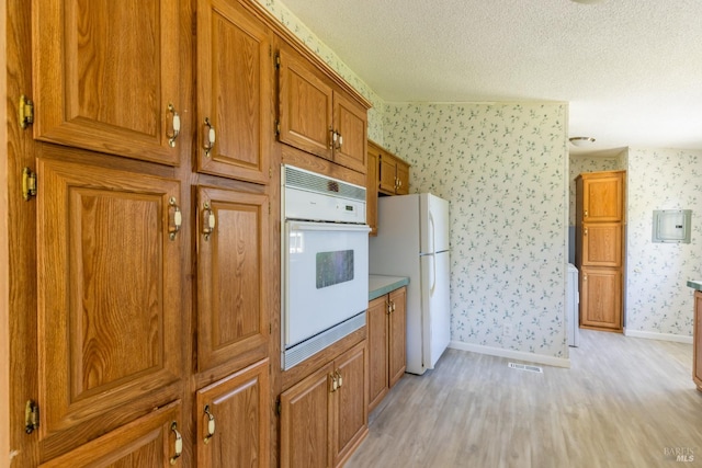 kitchen with light wood-type flooring, white appliances, electric panel, and a textured ceiling