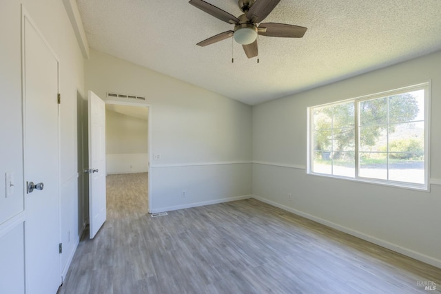 empty room featuring a textured ceiling, wood-type flooring, and ceiling fan