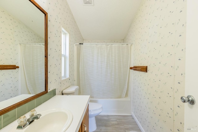 full bathroom featuring a textured ceiling, vaulted ceiling, toilet, shower / tub combo, and vanity