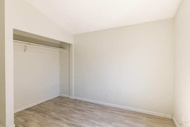 interior space featuring light hardwood / wood-style floors, lofted ceiling, and a closet