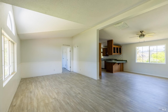 unfurnished living room with lofted ceiling, ceiling fan, hardwood / wood-style floors, and a textured ceiling