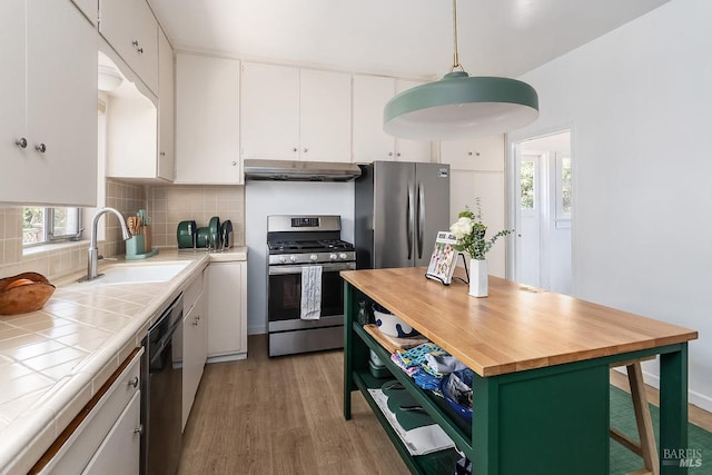 kitchen featuring sink, white cabinets, decorative light fixtures, and stainless steel appliances