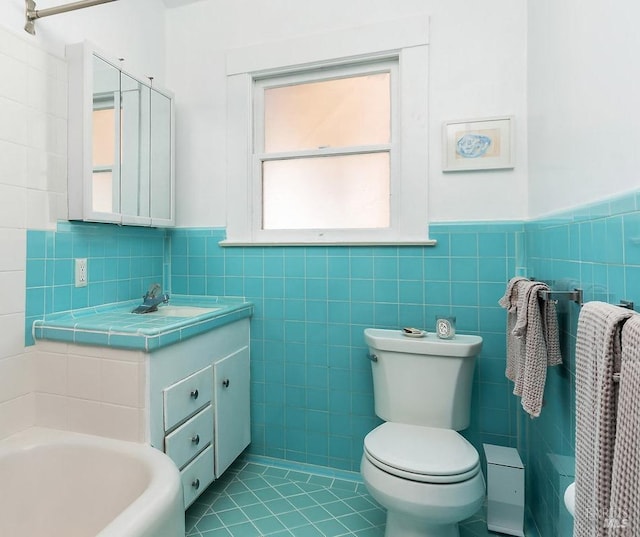 bathroom featuring tile walls, toilet, vanity, a tub to relax in, and tile patterned floors