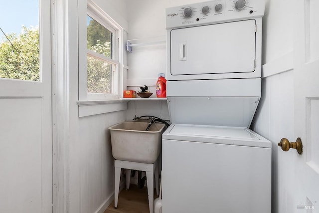 clothes washing area featuring a healthy amount of sunlight, stacked washer / drying machine, and sink