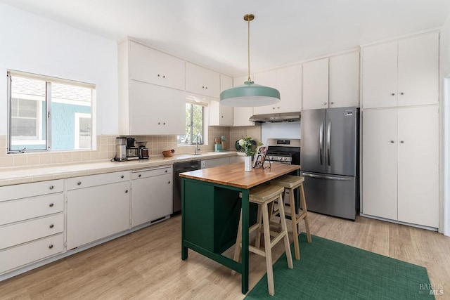 kitchen featuring stainless steel appliances, decorative light fixtures, plenty of natural light, and white cabinets