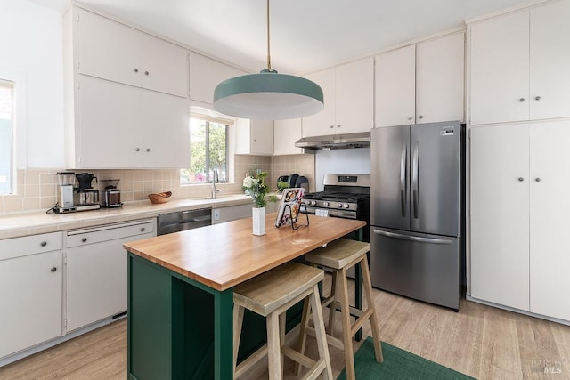 kitchen featuring appliances with stainless steel finishes, a kitchen breakfast bar, light hardwood / wood-style floors, white cabinets, and decorative backsplash