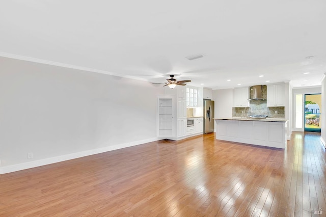 unfurnished living room featuring light hardwood / wood-style floors, crown molding, sink, and ceiling fan