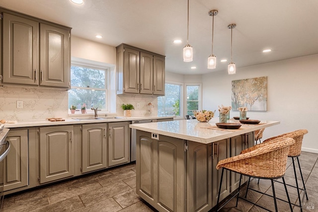 kitchen with a breakfast bar area, a sink, light countertops, a center island, and dishwasher