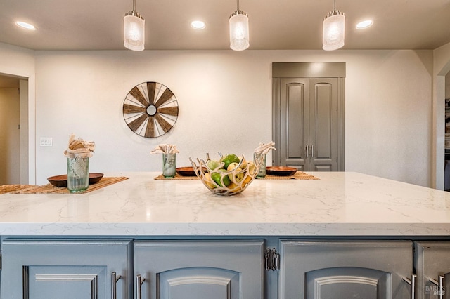 kitchen with gray cabinetry, hanging light fixtures, light stone countertops, and recessed lighting