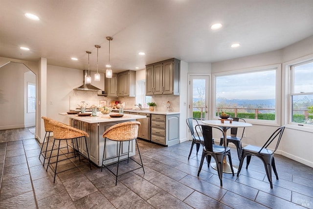 kitchen featuring light countertops, backsplash, baseboards, and wall chimney range hood