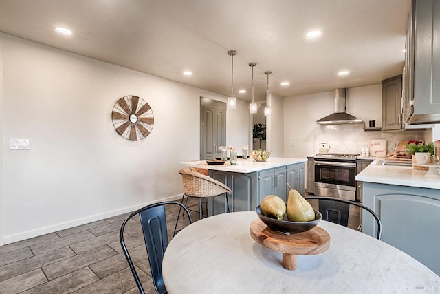 kitchen with wall chimney range hood, a center island, stainless steel range oven, and gray cabinetry