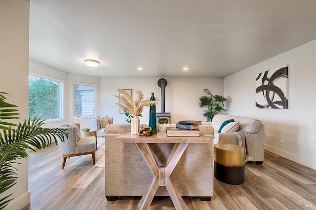 living area featuring a wood stove, baseboards, wood finished floors, and recessed lighting