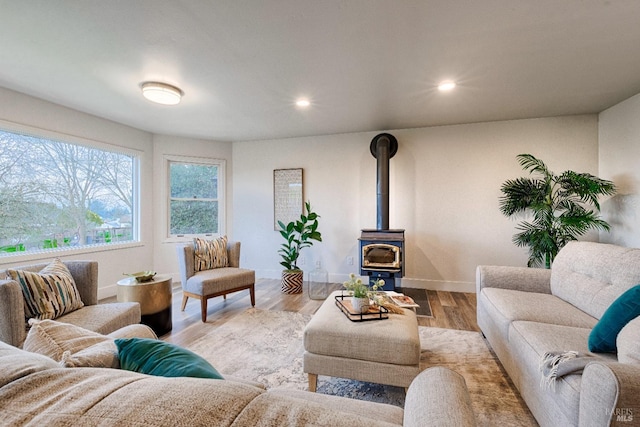 living area featuring recessed lighting, a wood stove, baseboards, and wood finished floors