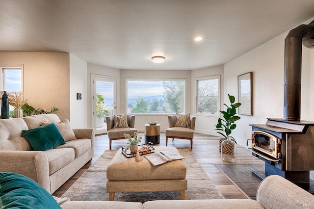 living room with recessed lighting, a wood stove, baseboards, and wood finished floors