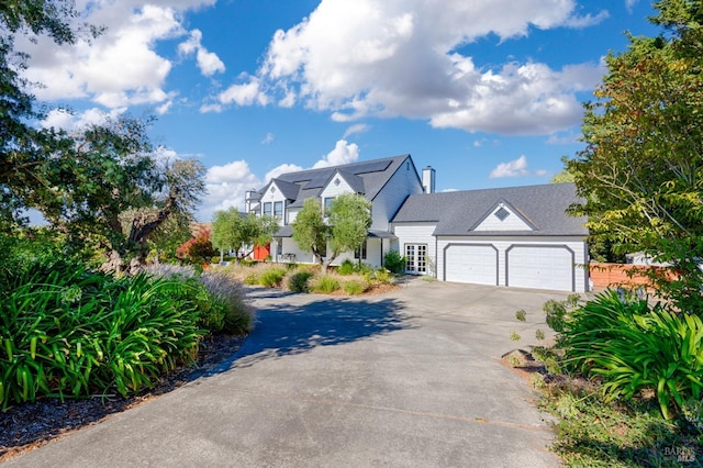 view of front of property featuring concrete driveway, an attached garage, and solar panels