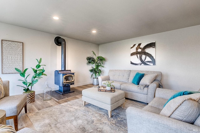 living area featuring recessed lighting, a wood stove, baseboards, and wood finished floors