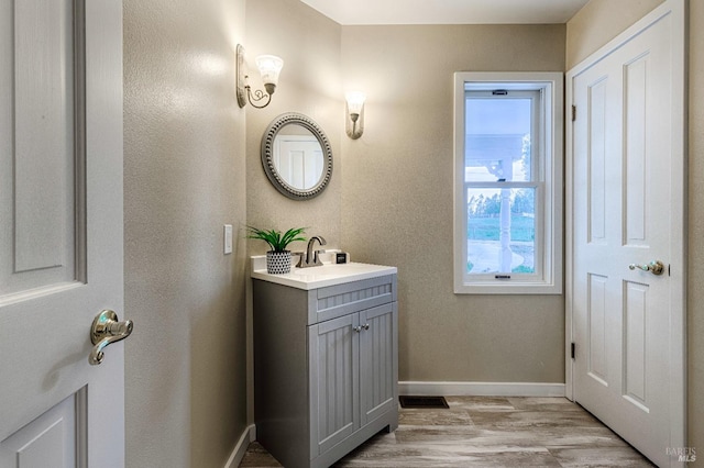 bathroom featuring visible vents, baseboards, wood finished floors, and vanity