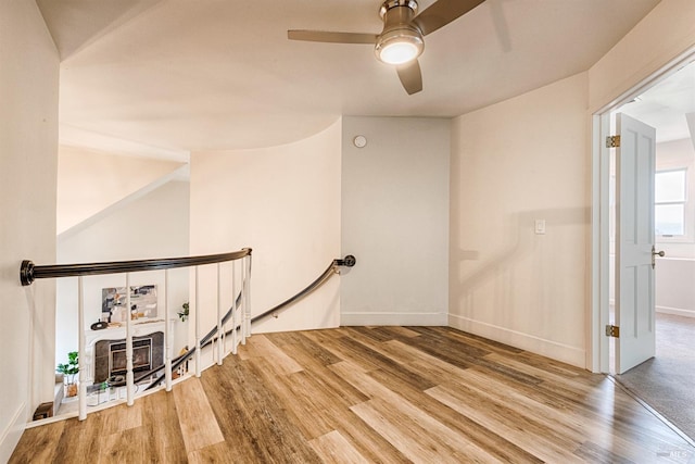 interior space with a ceiling fan, baseboards, and wood finished floors