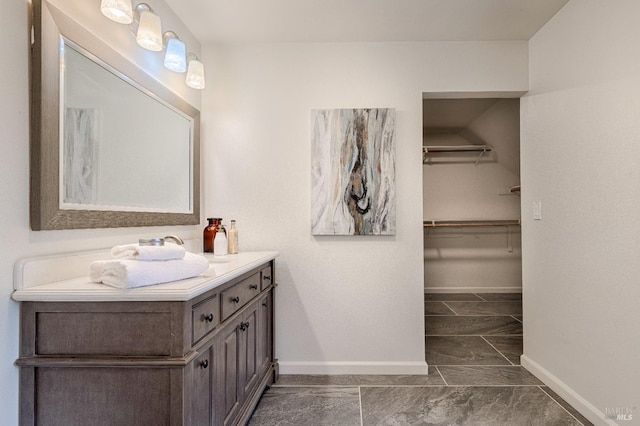 bathroom featuring vanity, baseboards, and a spacious closet