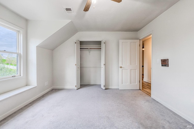 unfurnished bedroom with ceiling fan, light colored carpet, visible vents, baseboards, and a closet