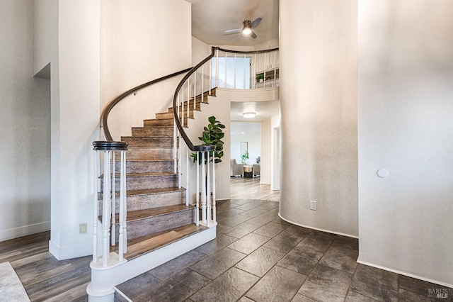 foyer with stone finish flooring, baseboards, stairway, and a high ceiling