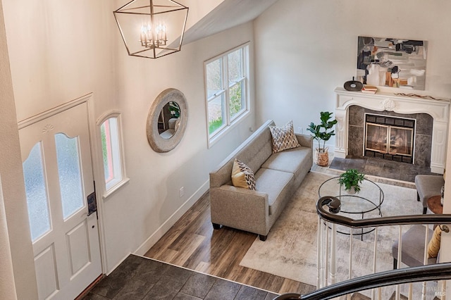 interior space featuring an inviting chandelier, wood finished floors, a high end fireplace, and baseboards