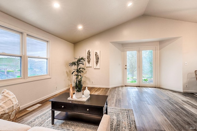 living room featuring vaulted ceiling, baseboards, and wood finished floors