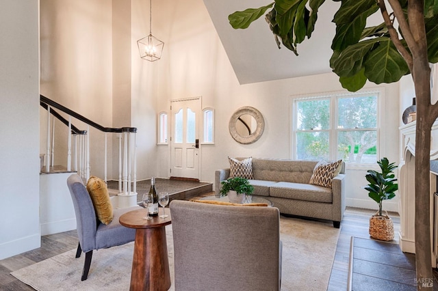 living room with stairs, a towering ceiling, baseboards, and wood finished floors