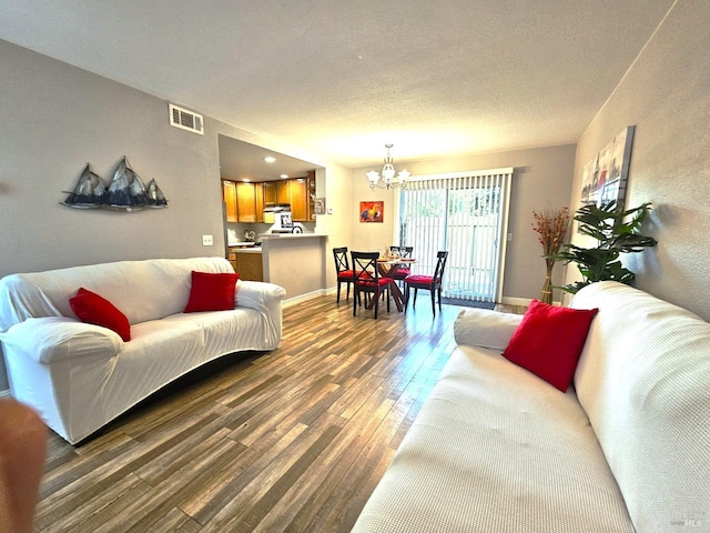 living room featuring an inviting chandelier, a textured ceiling, and dark hardwood / wood-style flooring