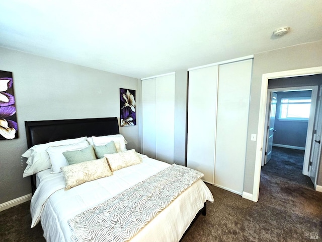 bedroom with baseboards, dark colored carpet, and multiple closets