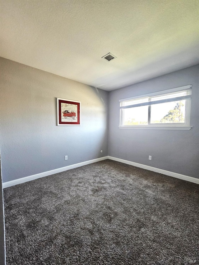 carpeted spare room featuring visible vents, a textured ceiling, and baseboards