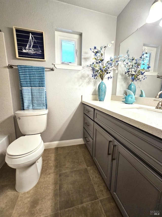 bathroom with a textured wall, tile patterned flooring, toilet, vanity, and baseboards