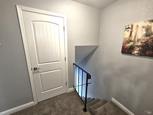 stairway with a textured wall, carpet floors, and baseboards