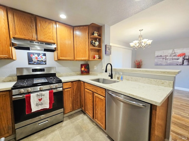 kitchen with sink, kitchen peninsula, stainless steel appliances, a notable chandelier, and light wood-type flooring