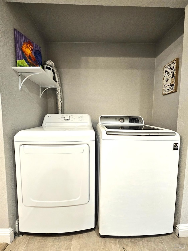 laundry area featuring laundry area, washing machine and dryer, baseboards, and light wood finished floors