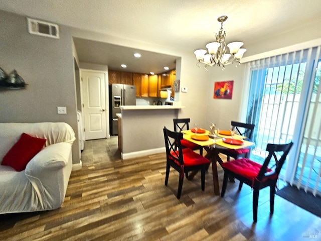 dining area with dark wood-style floors, visible vents, a notable chandelier, and baseboards