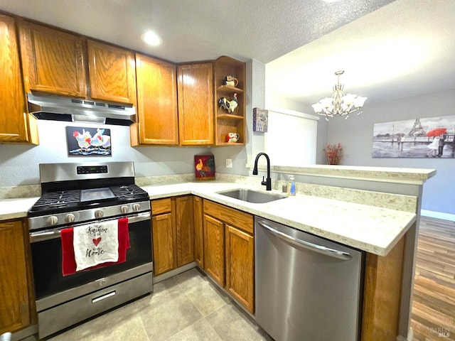 kitchen with light wood-type flooring, a chandelier, sink, kitchen peninsula, and appliances with stainless steel finishes