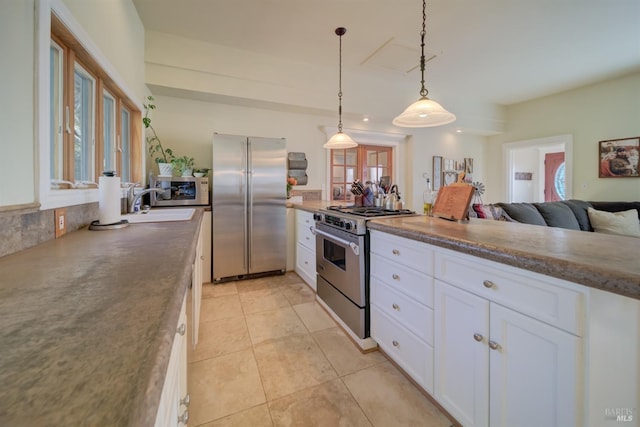 kitchen with stainless steel appliances, white cabinetry, decorative light fixtures, light tile patterned floors, and sink