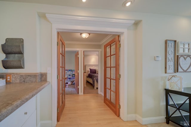 corridor featuring french doors, light wood-type flooring, and crown molding