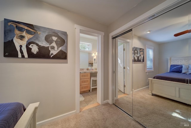 bedroom featuring connected bathroom, a closet, and light carpet