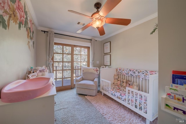 bedroom with light colored carpet, a crib, ceiling fan, and ornamental molding