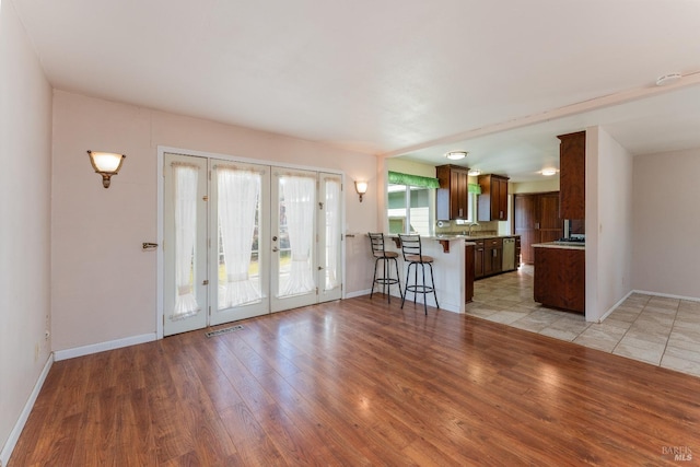 unfurnished living room with light hardwood / wood-style flooring, sink, and french doors