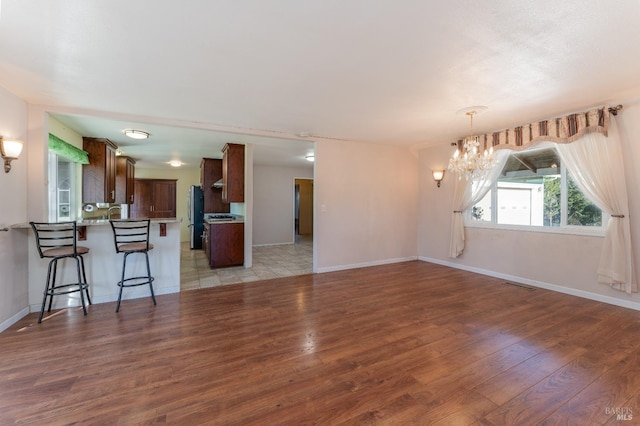 unfurnished living room featuring a notable chandelier and light hardwood / wood-style floors