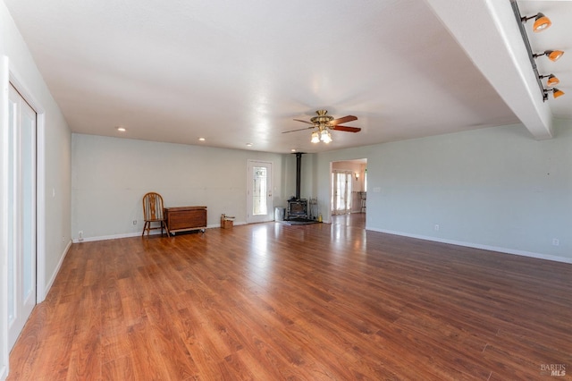 unfurnished living room with hardwood / wood-style flooring, ceiling fan, and a wood stove