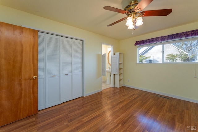 unfurnished bedroom featuring a closet, hardwood / wood-style floors, connected bathroom, and ceiling fan