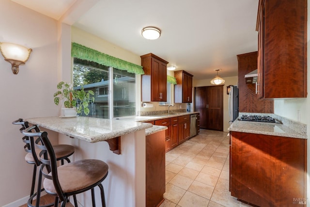 kitchen featuring pendant lighting, a breakfast bar, light stone counters, and kitchen peninsula